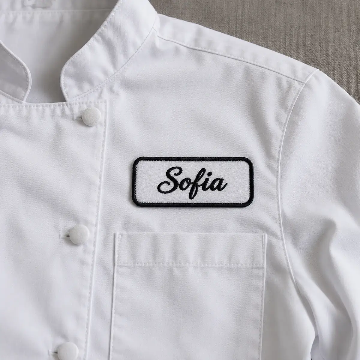 Embroidered Sofia script name patch on a white chef coat.