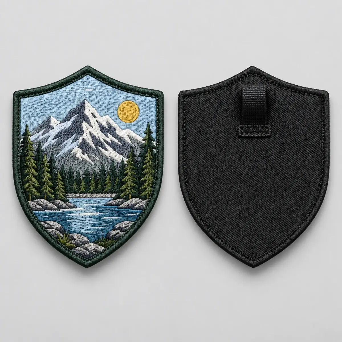 Embroidered mountain shield patch shown front and back with a fabric button loop.