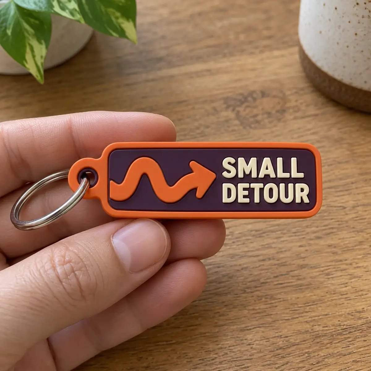 Orange PVC Small Detour keychain held in hand.