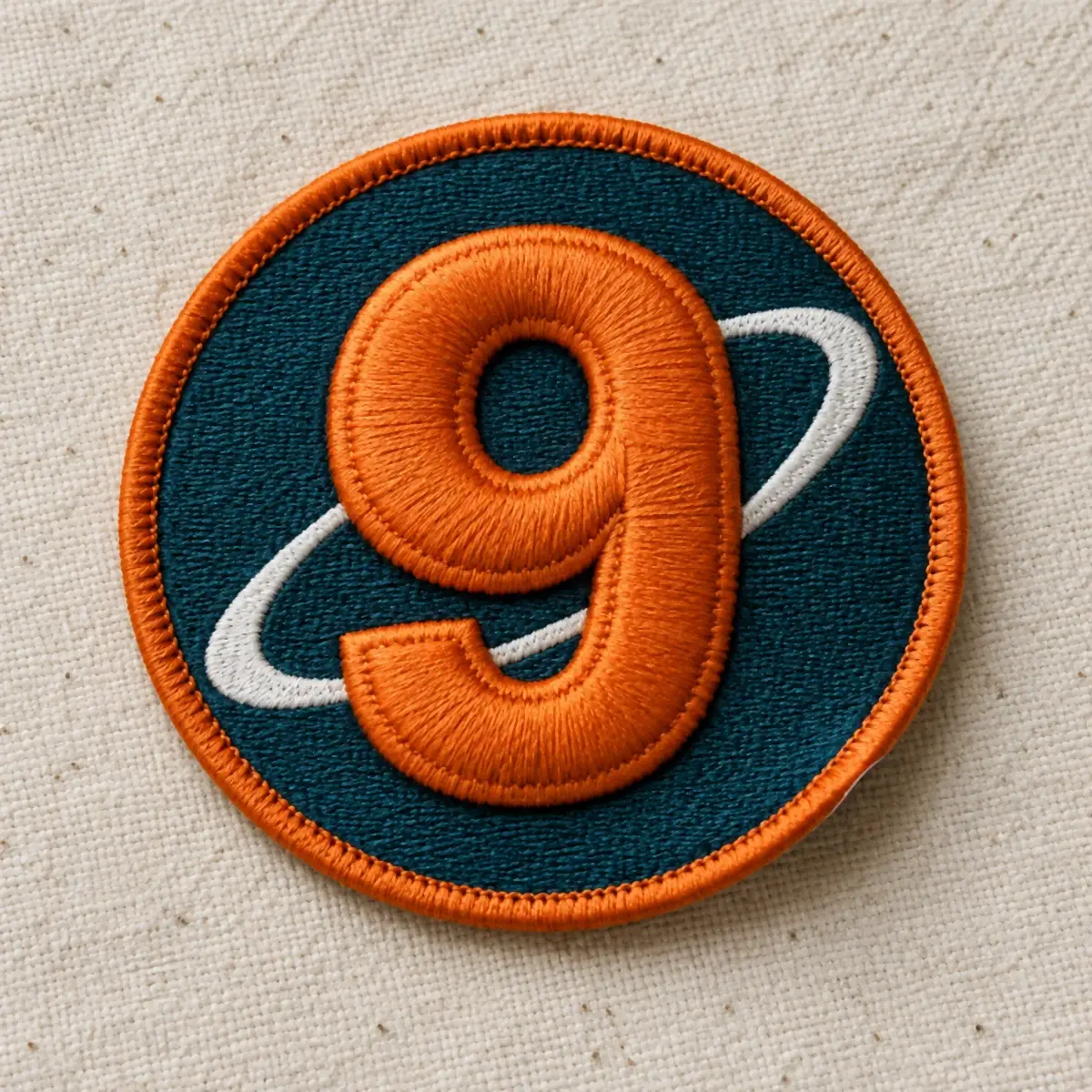 3D puff embroidered number 9 patch with an orange ring on navy.