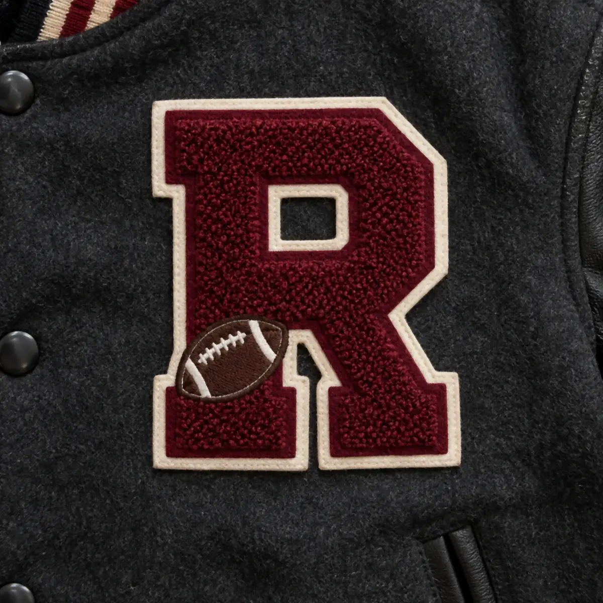 Maroon chenille letter R with a football on a black varsity jacket.