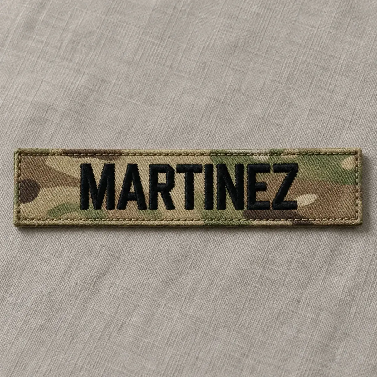 Embroidered MARTINEZ name tape in black lettering on multicam camouflage.