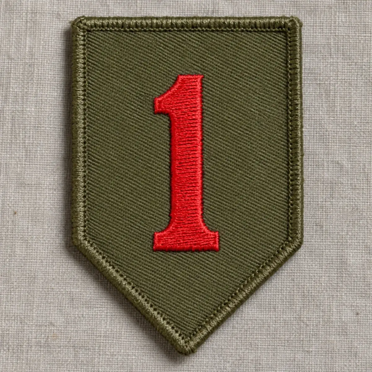Olive embroidered shield patch with a red numeral one on linen.