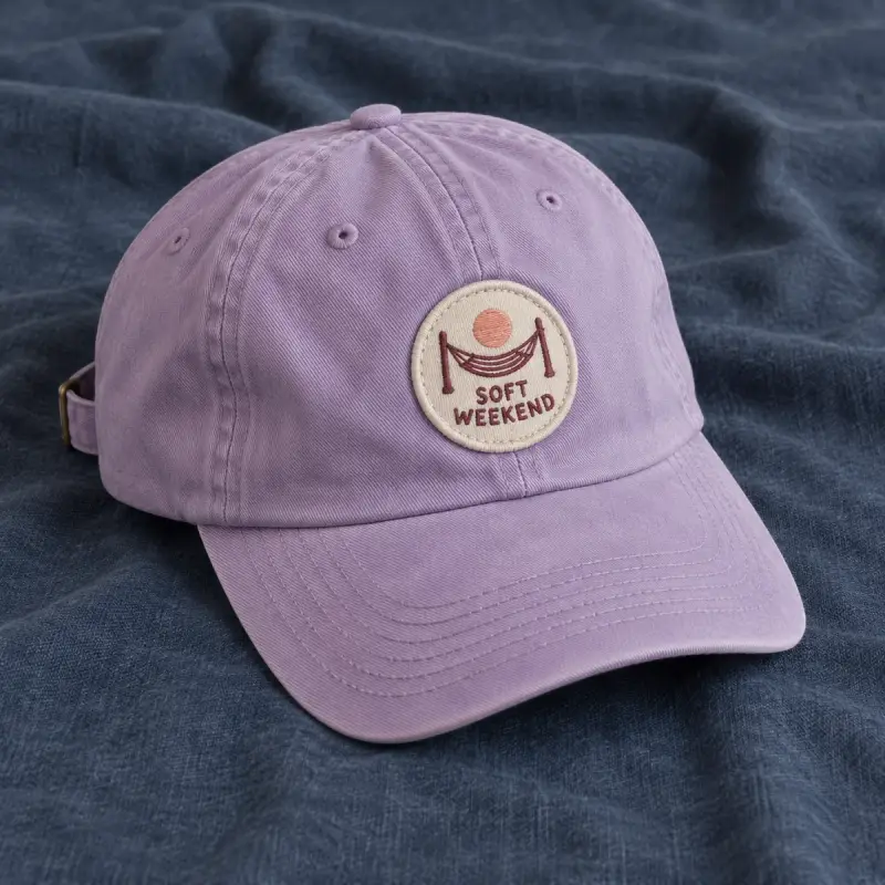 Round embroidered Soft Weekend hammock patch on a lilac cap.