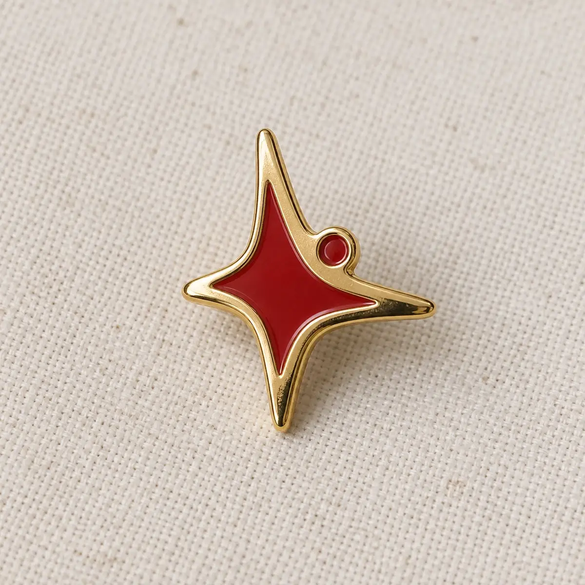 Gold four-point star lapel pin with red enamel.