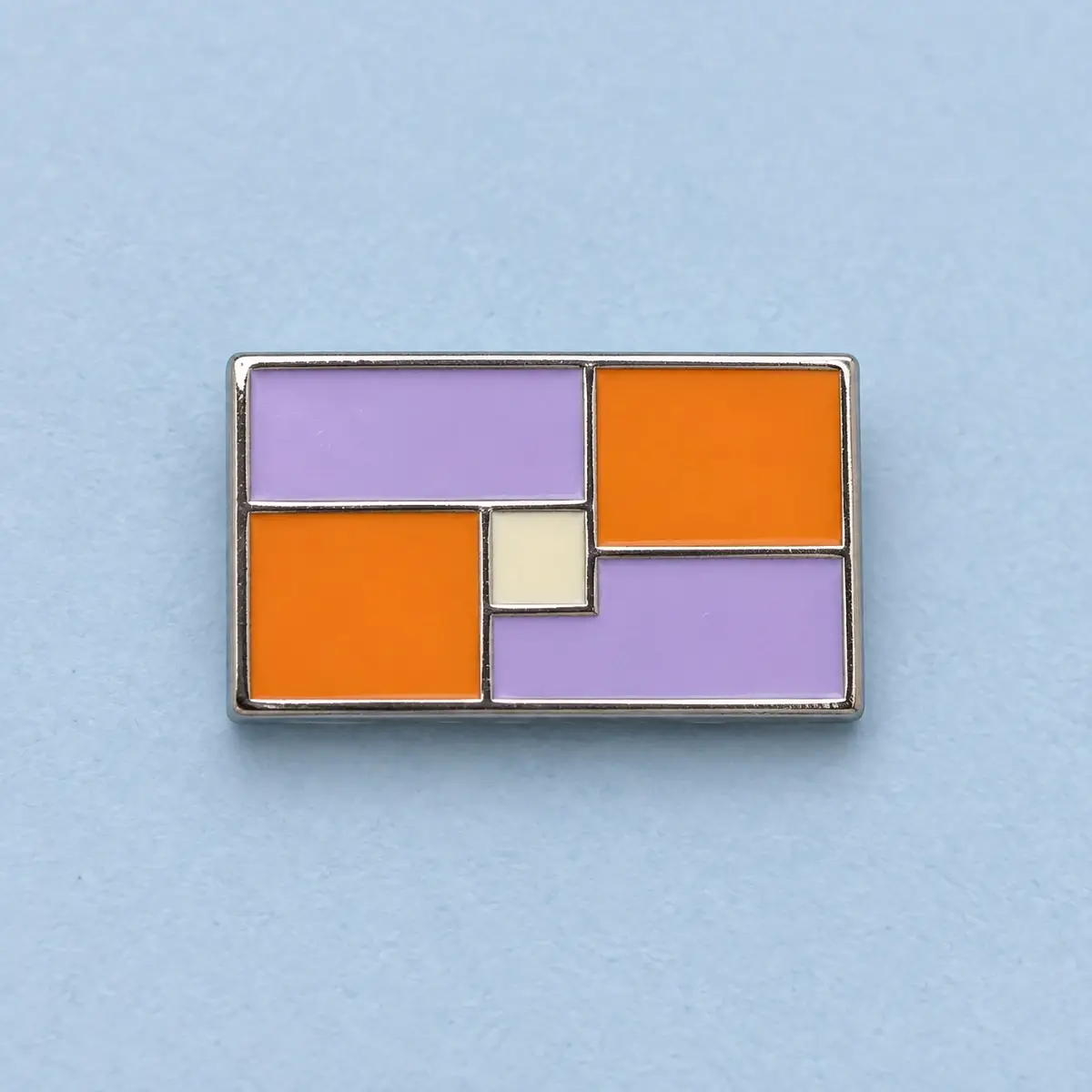 Rectangular silver lapel pin with lilac and orange color blocks.