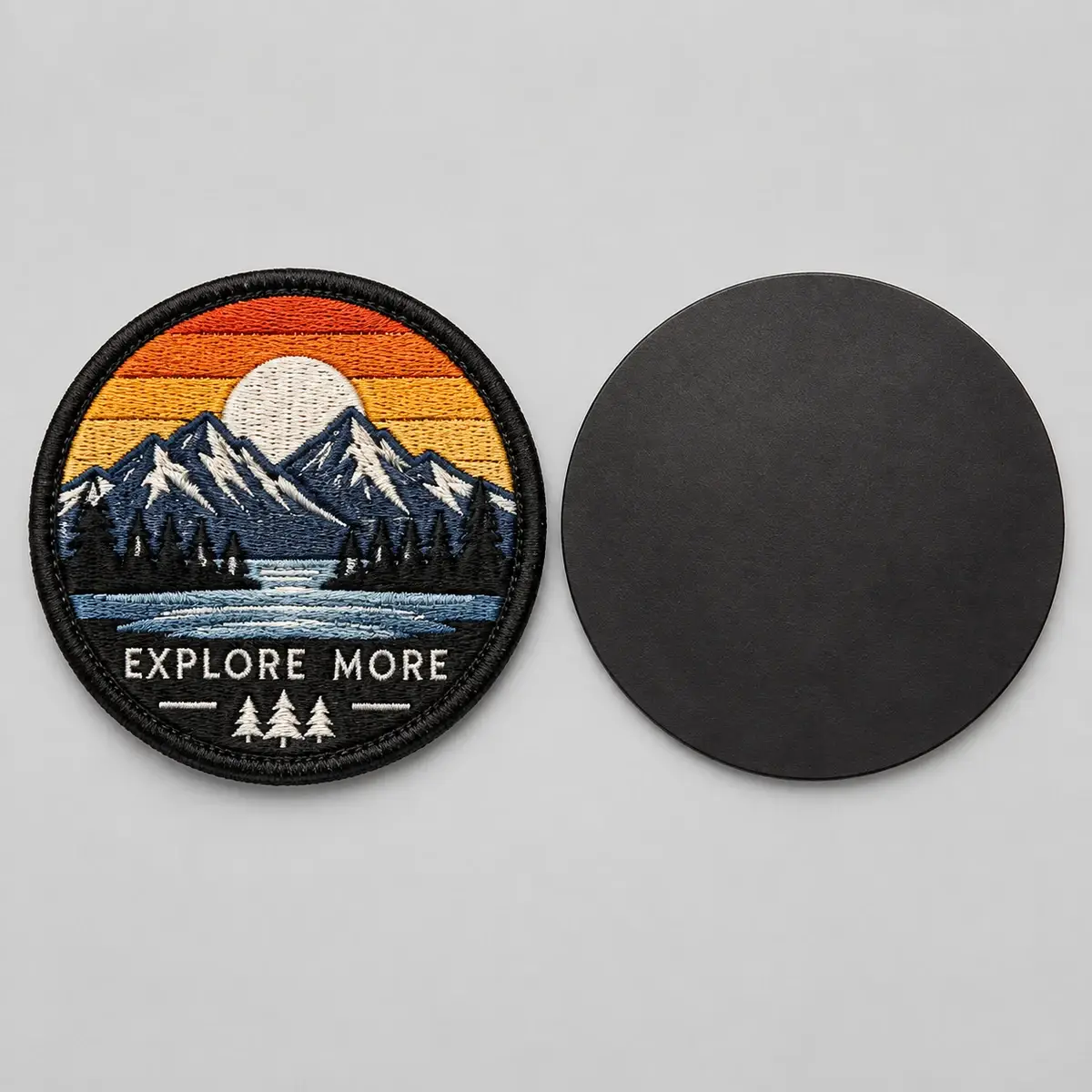 Round Explore More mountain patch beside its round magnetic backing.