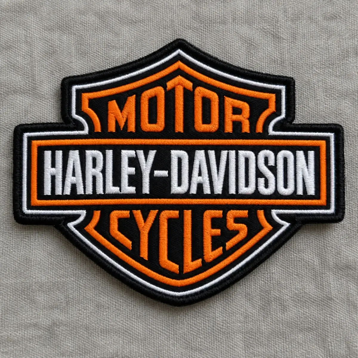 Embroidered orange, black and white bar and shield Motor Cycles logo patch.