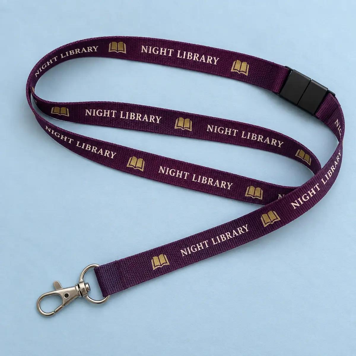 Burgundy Night Library lanyard printed with gold book icons.