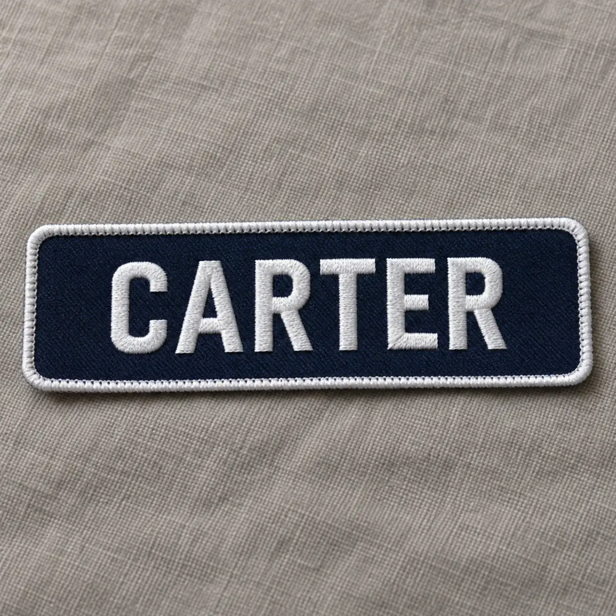 Navy embroidered CARTER name patch with a white merrow border.