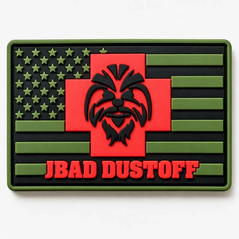Molded PVC subdued US flag patch in olive and black with a red cross and JBAD DUSTOFF lettering.