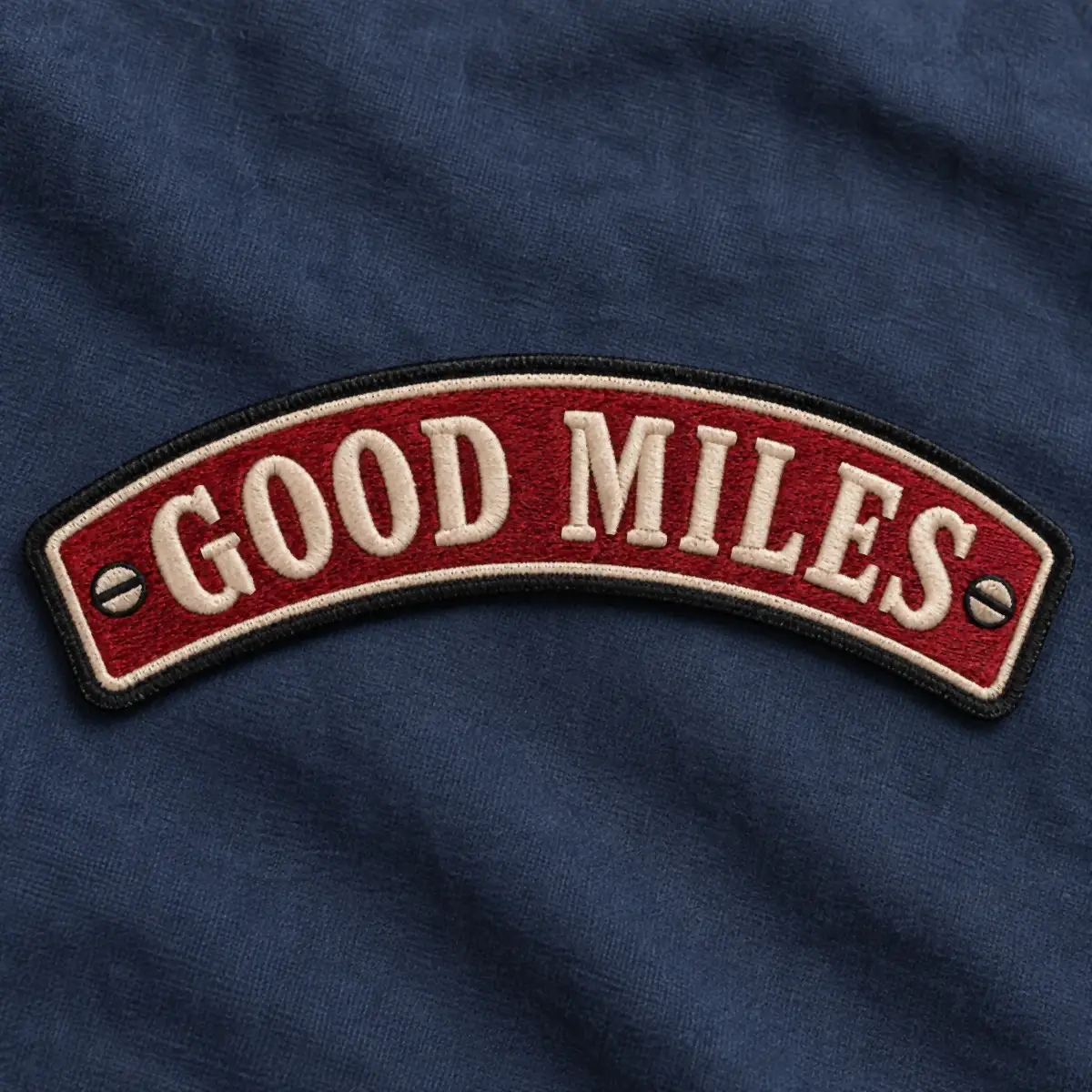 Red embroidered Good Miles rocker patch on navy fabric.
