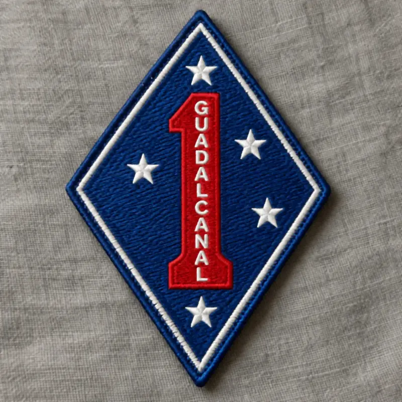 Embroidered blue diamond unit patch with a red numeral one reading GUADALCANAL and five white stars.