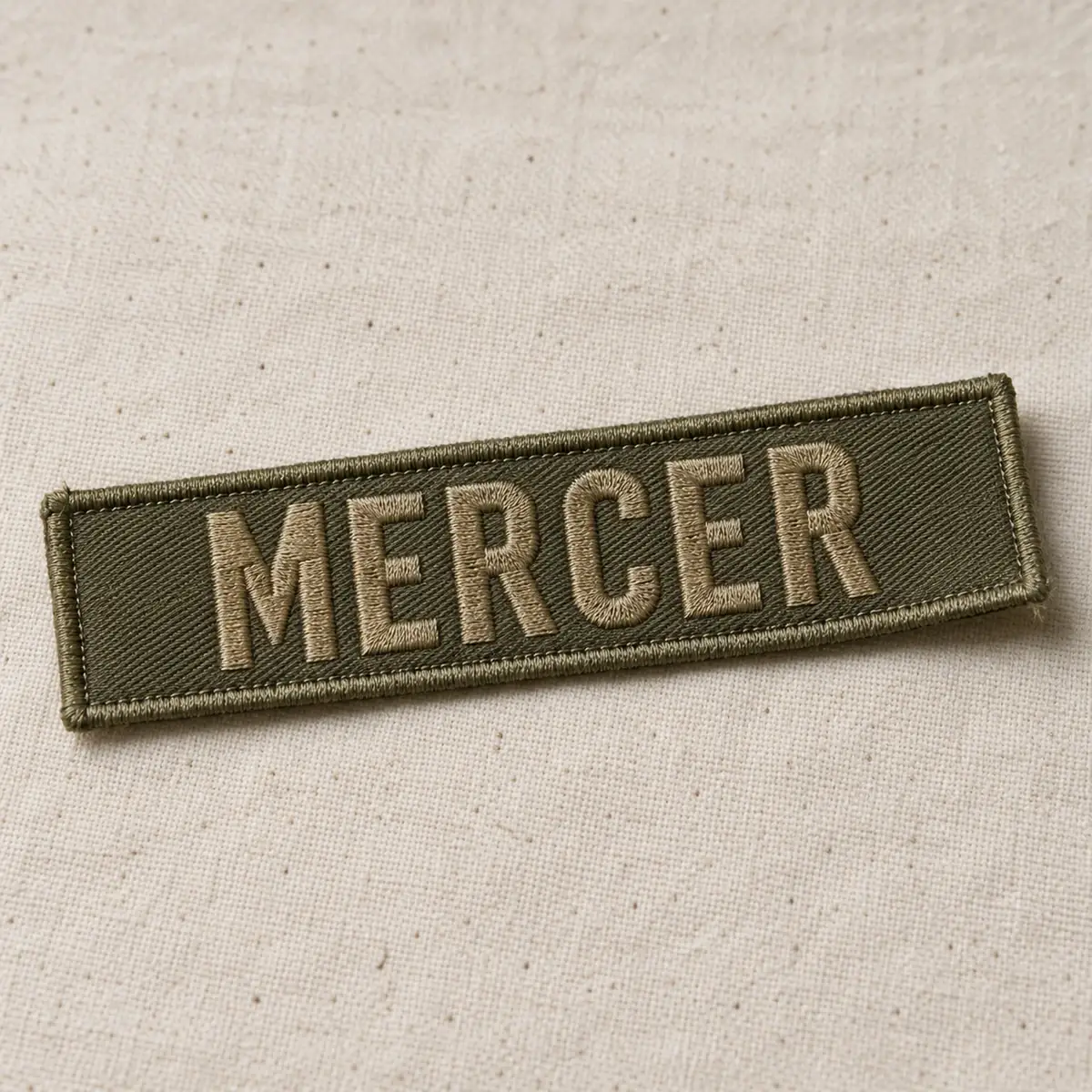 Olive embroidered MERCER name tape on canvas.
