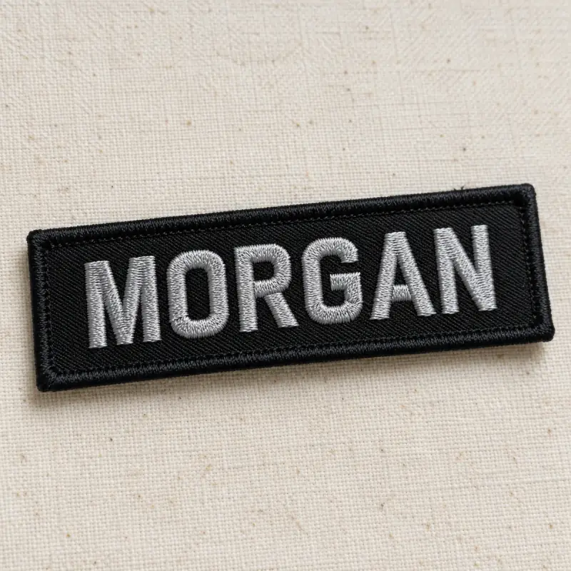 Black embroidered MORGAN name patch in silver lettering.