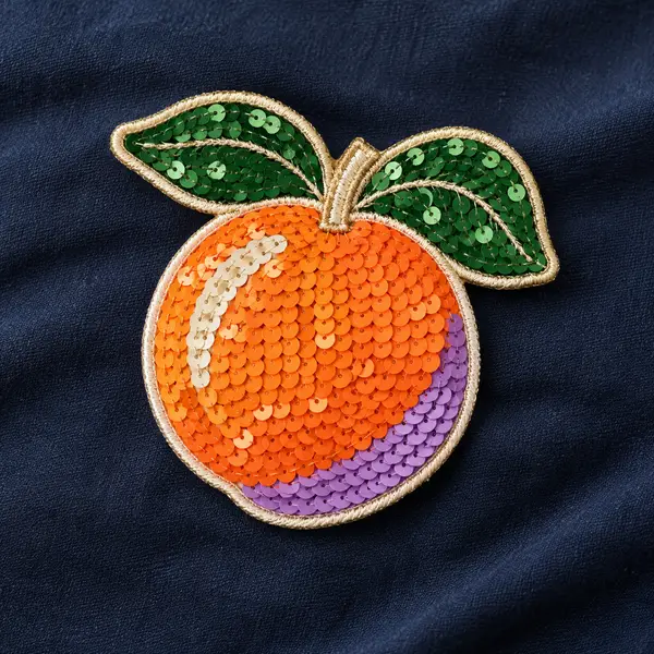 Orange fruit patch with colorful sequins and green leaves.
