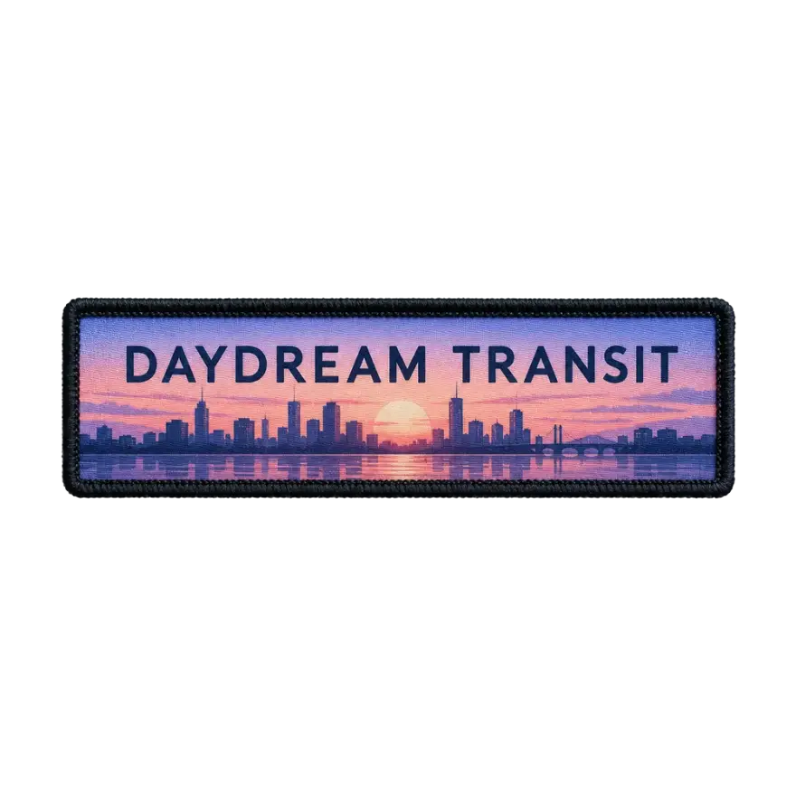 Printed name tape reading Daydream Transit over a sunset city skyline