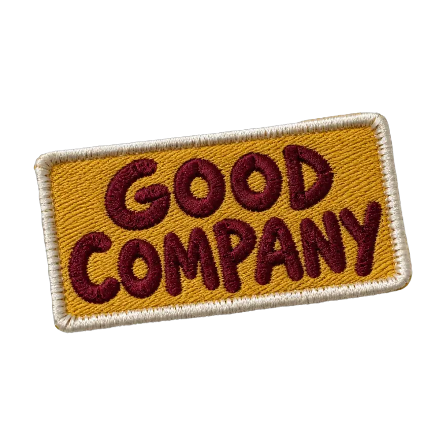 Rectangular embroidered Good Company patch in maroon thread on mustard twill